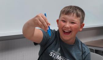 Child finds leech with tweezers in water.