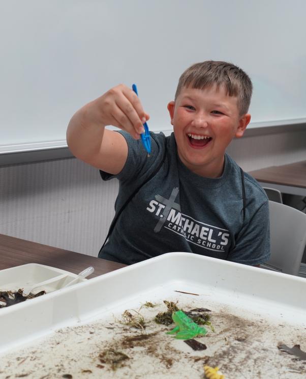 Child finds leech with tweezers in water.