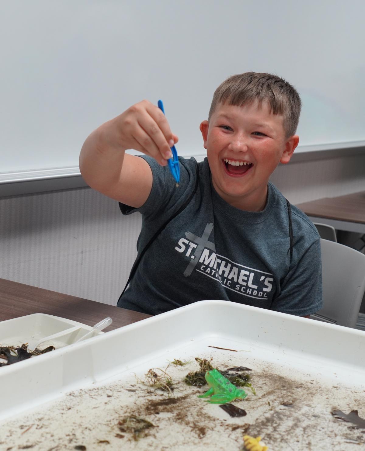 Child finds leech with tweezers in water.